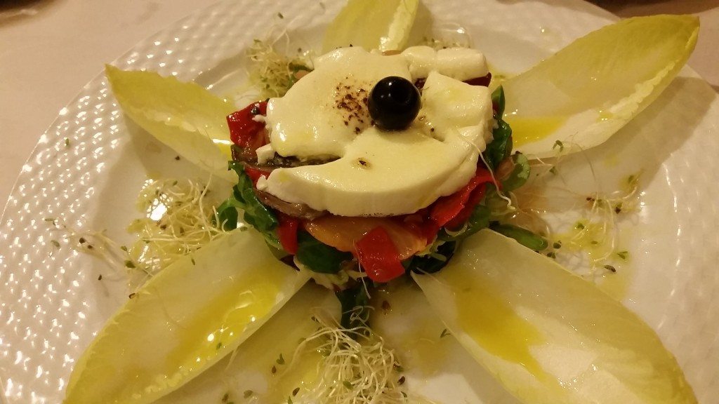A salad topped with anchovies, grilled peppers and goat cheese.
