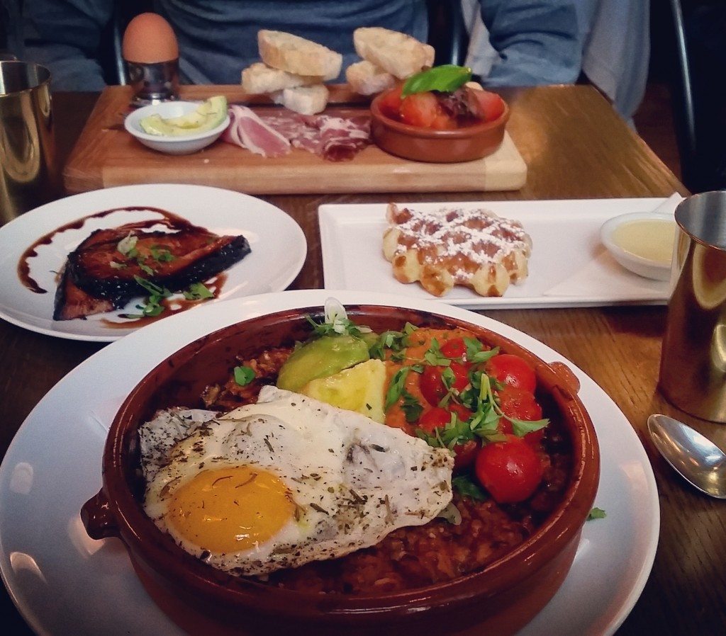 Breakfast paella and La Sante (soft boiled egg, marinated tomato salad, olive tapenade, avocado, charcuterie and grilled ciabatta. Belgian waffle with pistachio rosewater white chocolate sauce and a side of bacon.